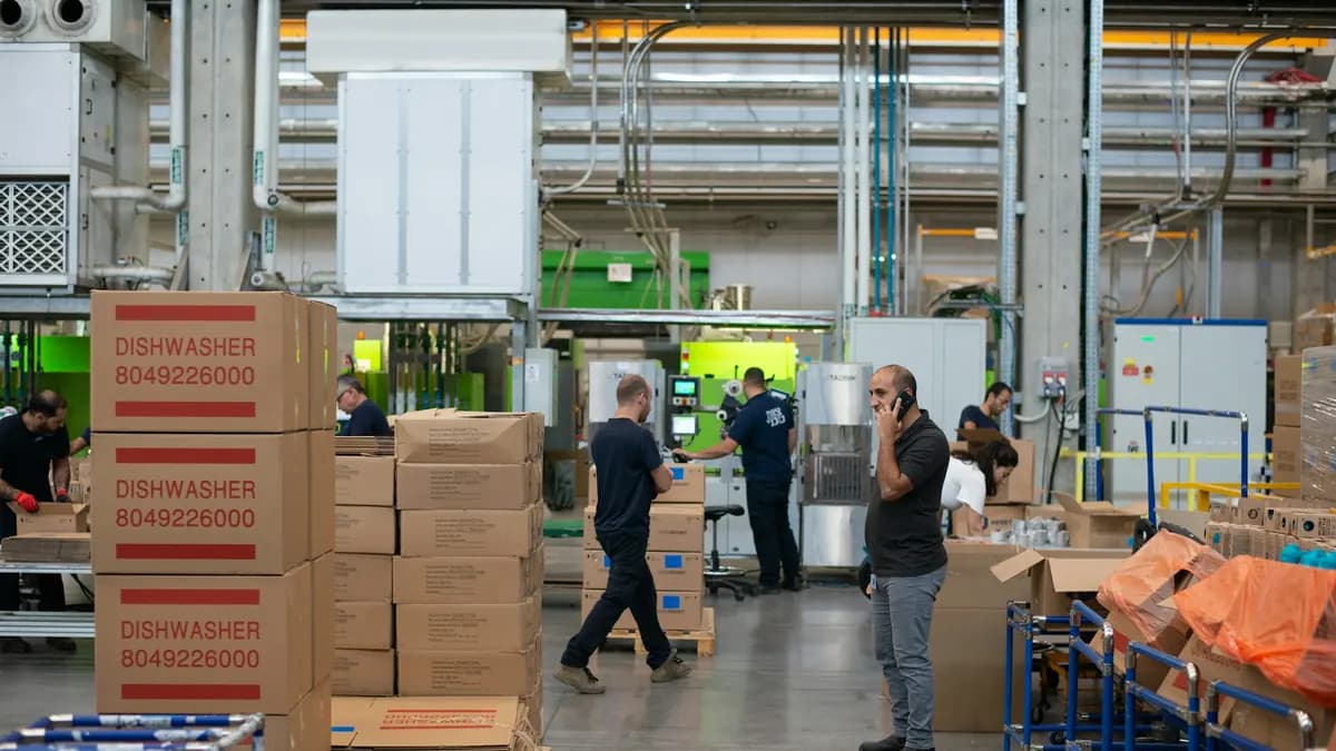 A warehouse worker beside stacks of cardboard boxes.